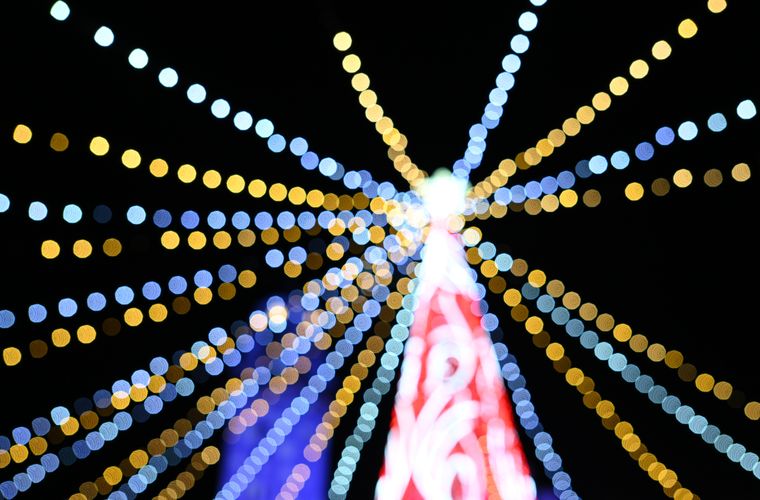 Die Spitze eines rot-weiß geschmückten Weihnachtsbaums ist fotografiert. Der Fokus ist total daneben, was einen 
schönen Effekt erzeugt, da die Lichter der den Baum umgebenden Lichterketten so out-of-focus sind und "bokeh balls" 
erzeugen.