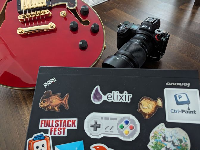 Eine Komposition aus 3 Gegenständen, die mein aktuellen Leben beschreiben. Eine rote semi-akustische Gitarre, eine
schwarze digitale Kamera und ein schwarzes Laptop von Lenovo mit Stickern darauf.