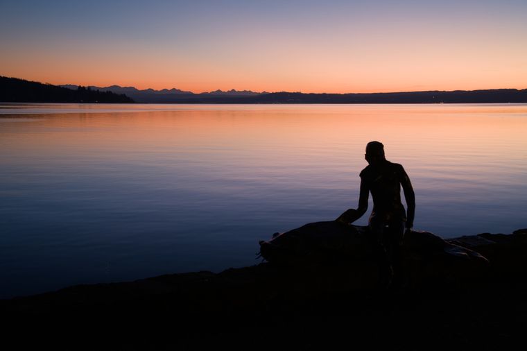 Der Ammersee am Abend, er liegt still in seinem Bett. Das letzte Licht der Sonne lässt den Horizont und die Berge 
am dort orange leuchten, während sonst schon das Blau der Nacht Einzug hält. Im Vordergrund ist die Silhouette der 
Statue "Loreley vom Ammersee", eine Jungfrau, einen großen Waller reitend.